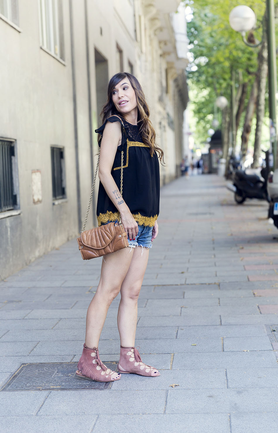 look de street style con top negro y ribete dorado de estilo romántico y shorts vaqueros