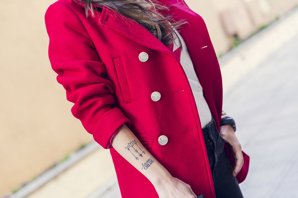 look de street style con abrigo marinero rojo de Tintoretto, jeans negros desgastados, botines con tachuelas, camiseta con print de David Bowie