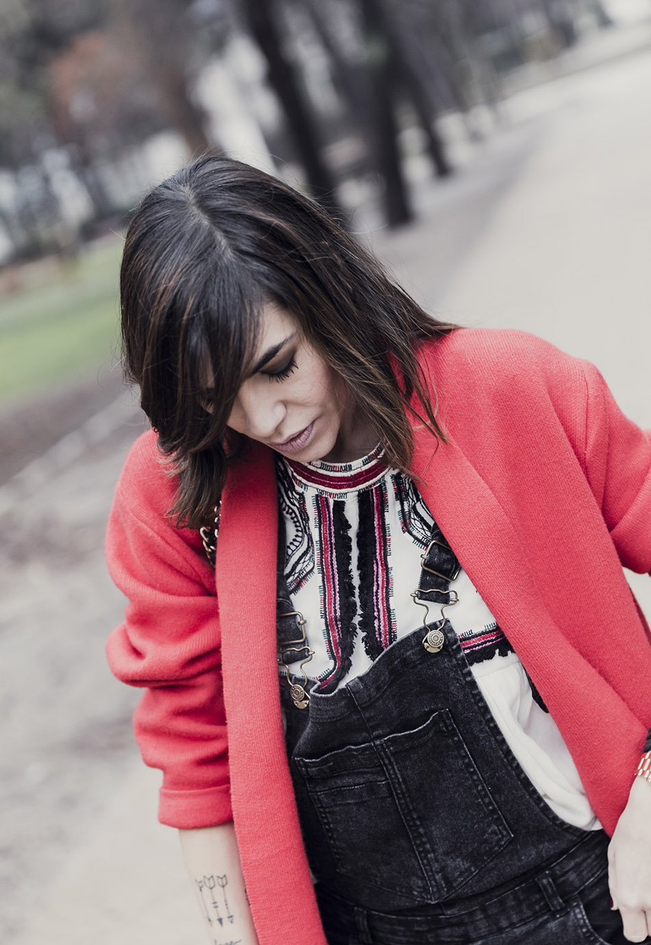 look de street style con abrigo rojo, peto vaquero negro, blusa bordada, botines con tachuelas y bolso purificación garcía