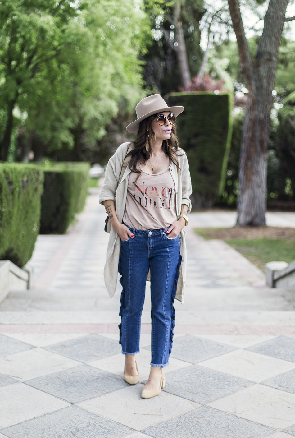 look de street style con sombrero de color beige, camiseta con mensaje, jeans de mango con volantes en los laterales, zapatos Chanel