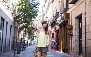 look de street style con top amarillo de tirantes combinado con shorts de ante en color marrón, zapatos de tacón en charol de mango y bolso de miu miu