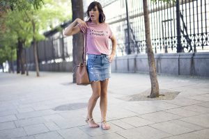 street style con camiseta con mensaje de a bicyclette, mini vaquera con desgastados de Zara y sandalias planas con animal print