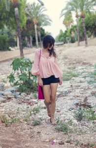 look de street style con blusa con mangas abullonadas en rosa empolvado de sheinside, shorts denim de mango en color negro, sandalias anudadas en el tobillo y bolso fucsia de hakei